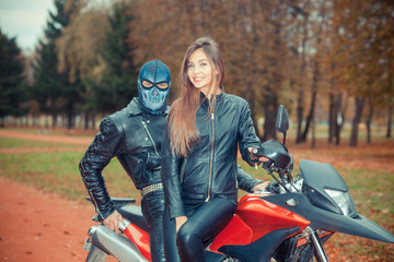 Fototapeta na wymiar portrait of a beautiful hipster girl on a sports motorcycle with a guy in the skull mask