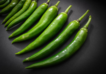 Hot green pepper pods on black background