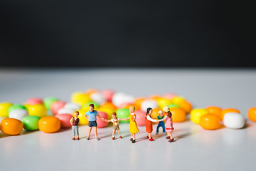 Miniature group of children standing colorful candy background using as family and education concept