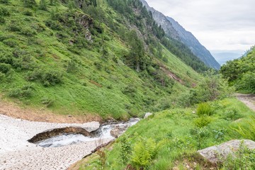 Fototapeta na wymiar Reste der Eisdecke und Schneedecke über einen Gebirgsbach im Sommer, Österreich
