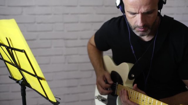 Man studying music with electric guitar at home