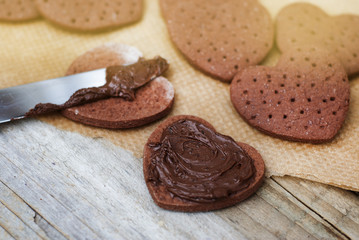 Delicious heart shape homemade chocolate cookies on rustic wooden background. Sweet chocolate dessert or snack.