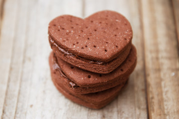 Delicious heart shape homemade chocolate cookies on rustic wooden background. Sweet chocolate dessert or snack.