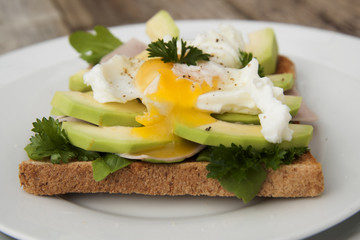 Bread toasts with avocado, eggs and greens. Tasty breakfast. Wood background. Isoalted.