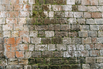 The texture of the old masonry of stone and concrete. The wall on the streets of Italy. Covered with moss and grass, ancient blocks. Historical paving and paving slabs.