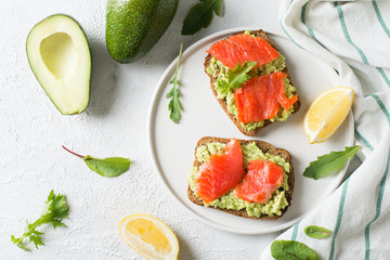 Toasts with avocado and salmon on plate