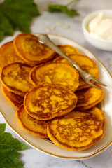 Homemade pumpkin pancakes served with sour cream on a light background.