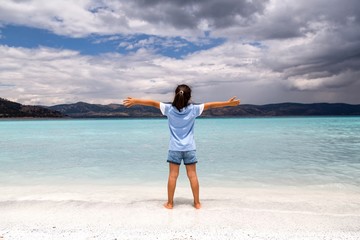 girl standing near turquoise lake