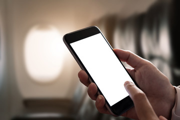 Mockup image of a hand holding a smart phone with blank desktop screen on airplane window, Blank...