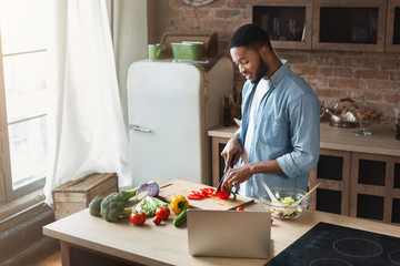 African-american man preparing salad in loft kitchen