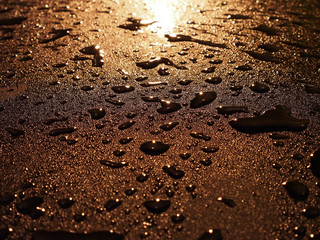 water droplets on dark metallic surface reflection gold light at night after rain