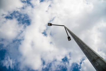 Led street light on concrete pylon, blue sky with white clouds in the background.