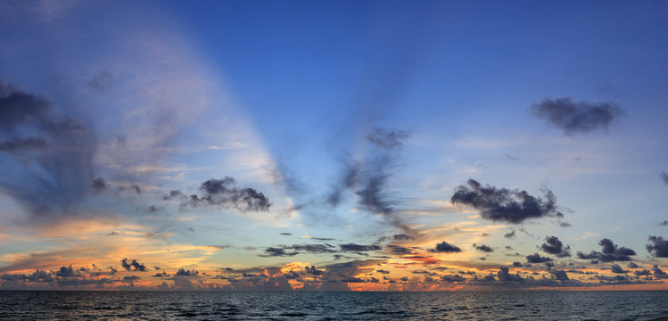 Abstract seascape panoramic sky background - Sunset colors with beautiful hues of blue, orange, purple pink and yellow. Calm seas/ocean in the bottom of the frame. Minimalistic simple background image