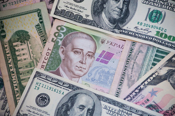 500 paper note of Ukrainian currency hryvnya lying under many American dollars