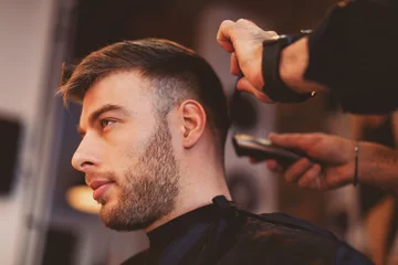 Crédence de cuisine en verre imprimé Salon de coiffure Bel homme chez le coiffeur se fait couper les cheveux