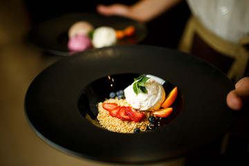 Balls of ice cream with berries in the black plate