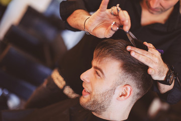 Obraz na płótnie Canvas Handsome man at the hairdresser getting a new haircut