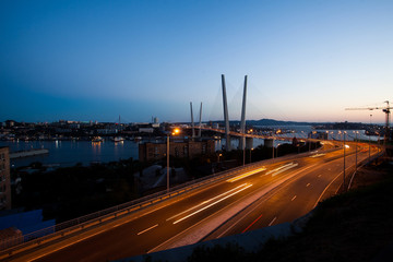 Fototapeta na wymiar Golden cable-stayed bridge road car traffic from above. Modern Vladivostok Russia night illumination. Old and modern central buildings. 