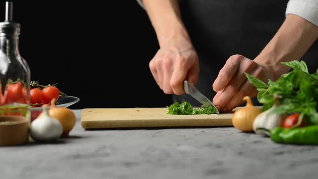 Chef cutting green herbs for cooking sauce for pasta, pizza or salad