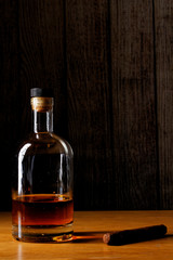 Bottle of whiskey and Cuban cigar on the wooden background