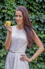 Young girl in a white dress in a summer park with apple

