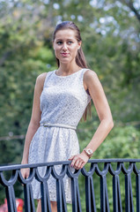 Young girl in white dress in summer park on the bridge
