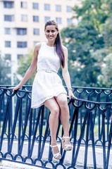 Young girl in white dress in summer park on the bridge

