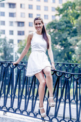 Young girl in white dress in summer park on the bridge
