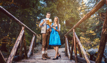 Woman and man with beer standing on bridge in Bavaria