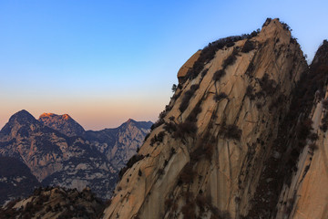 Huashan, Mount Hua - Huayin, near Xi'an in Shaanxi Province China. Cliff Scenery with Steep Vertical Drop-off, Famous yellow granite mountains of China. Layers of Mountains in the distance, exotic