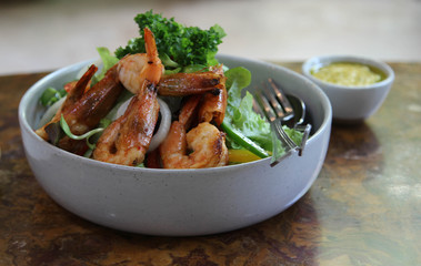Prawn salad in white  bowl and sauce on wooden table.