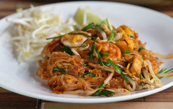 Pad Thai, Thai fried rice noodles with shrimp and vegetables on white plate.