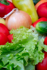 Vegetables on wooden cutting board. Vegetables: lettuce, onions, tomatoes, cucumbers, onions, carrots, red sweet peppers.
