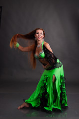 Beautiful woman dancing belly dance sexy Arabian Turkish oriental professional dancer in a bright, carnival shining suit with long brown healthy hair. Exotic belly dance star