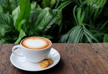 One Cup of Hot Cappuccino Coffee with Cookies Served on Wooden Table with Blurred Green Tree Leaves in Background  