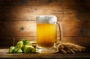 Mug of beer with green hops and wheat ears
