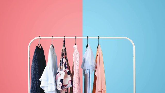 Women's clothing on a white clothes hanger on pink and blue pastel colors background.