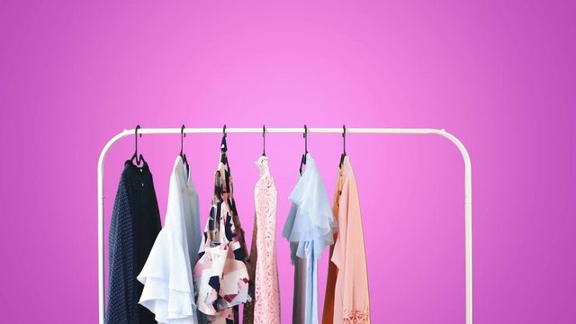 Women's clothing on a white clothes hanger on different pastel colors background.