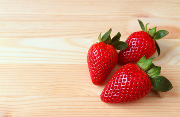 Three Vibrant Red Color Fresh Ripe Strawberry Fruits Isolated on Wooden Table with Free Space for Text or Design 