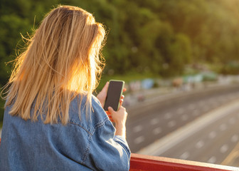 girl taking pictures of a landscape, close-up of a phone in her hand at sunset