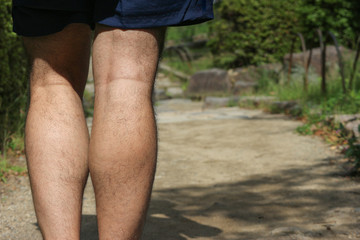 backside of healthy running man legs with copy space  walking way background.