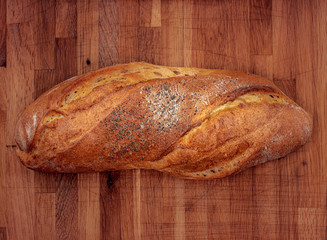 Fresh brown bread on wooden board, top view