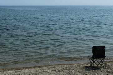 Black tourist chair on the shore of Lake Baikal
