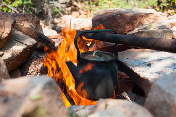 kettle is boiling on burning wood in large flames