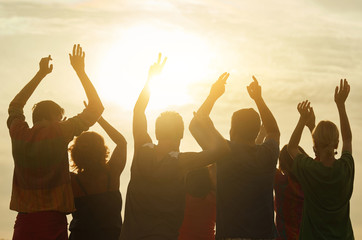 Happy people put hands up, back view. Posing for photo, sunrise background.