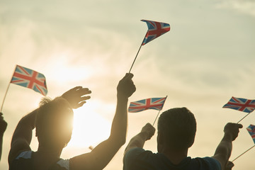 Two men with british flags. Cloudy and sunny sky background.