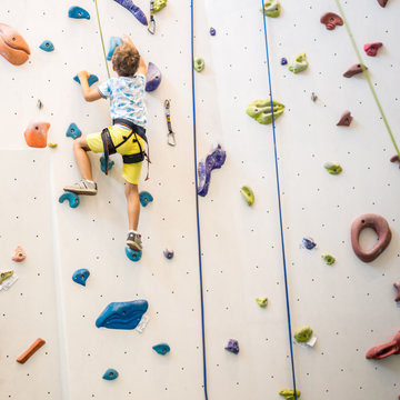 young boy is climbing on artificial climbing wall