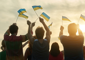 Small ukrainian flags. Back view. Blue and yellow flags. Evening sky bakground.