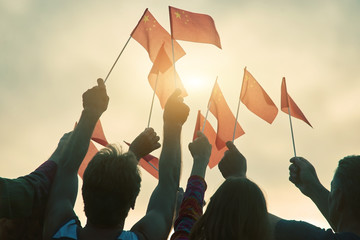 People waving chineese flags. Chineese patriotic family against evening sky background.