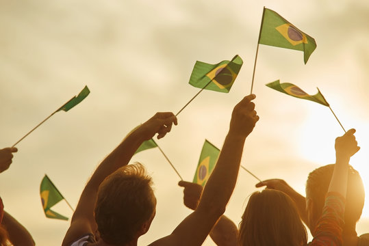 Brazilian patriots with flags outdoor. Silhouette of patriotic brazilian family, rear view.